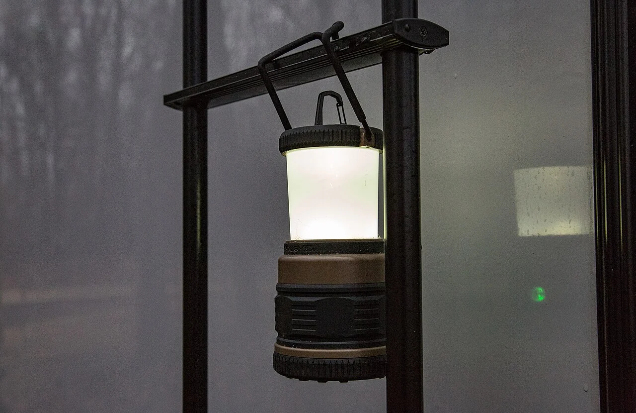 A portable LED lantern hanging beside a window.